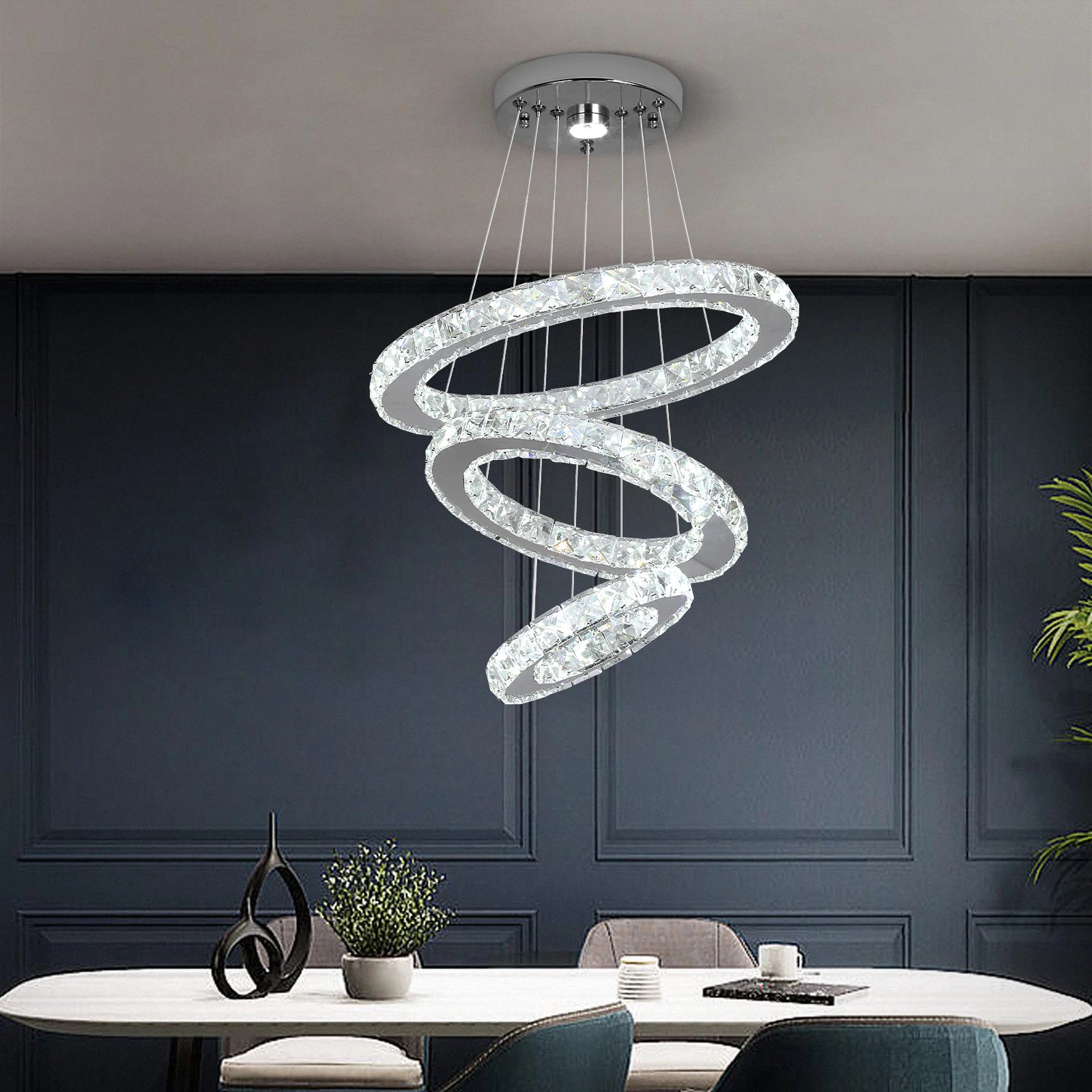 Modern spiral chandelier hanging above a dining table with a dark wall background