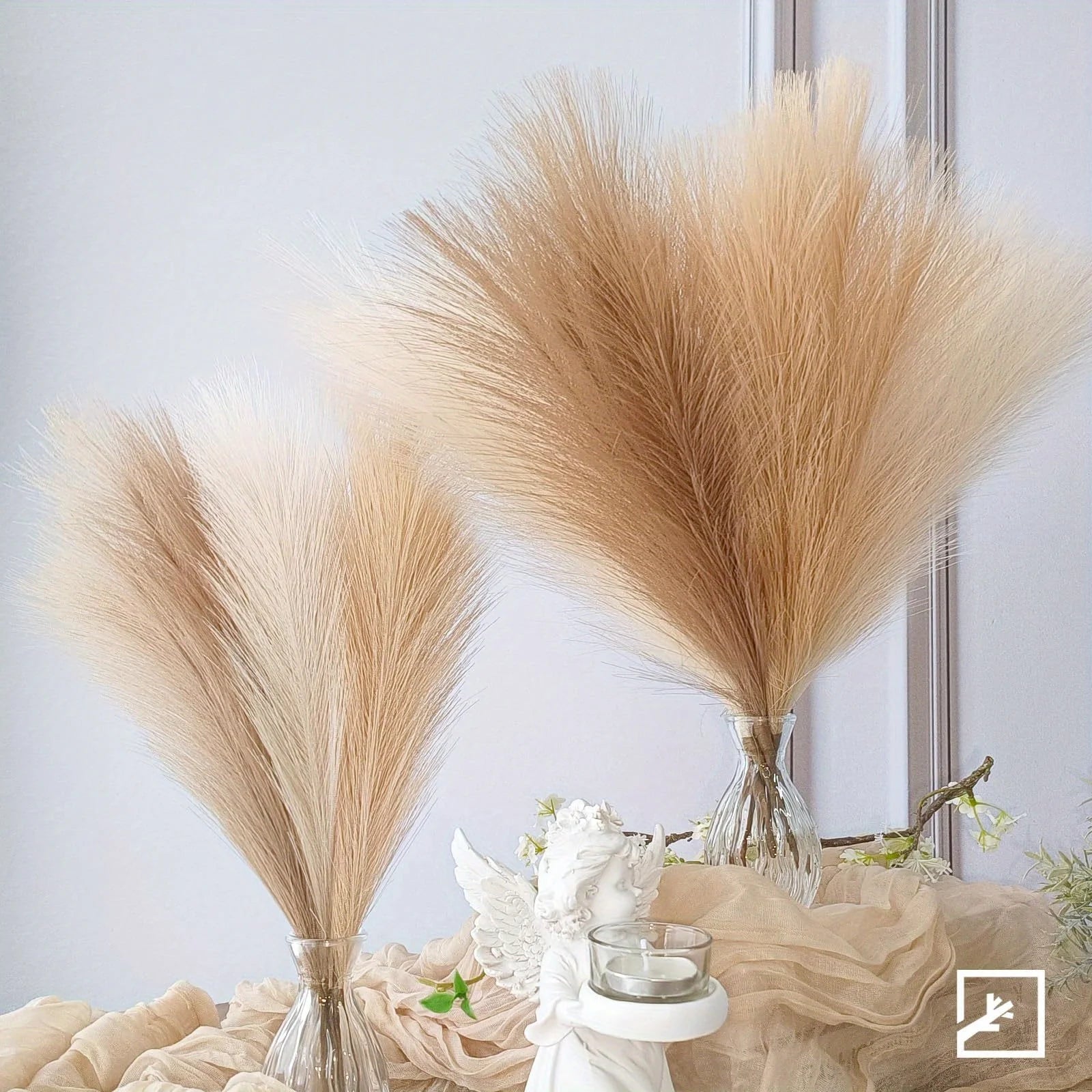 Two large pampas grass arrangements in clear vases on a decorative table.
