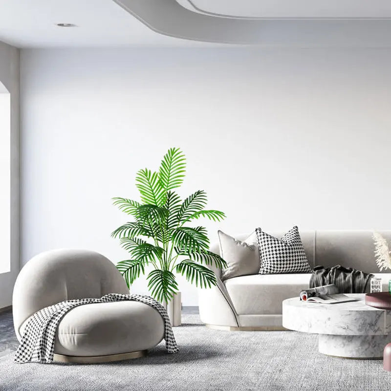 Modern living room with a gray armchair, sofa, and decorative plant.