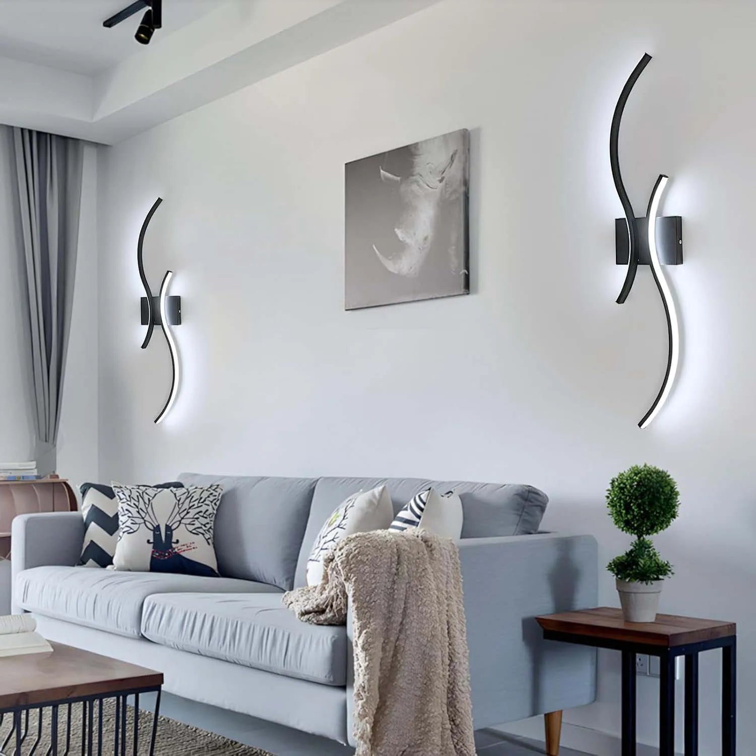 Modern living room with a gray sofa, decorative pillows, and wall lights.