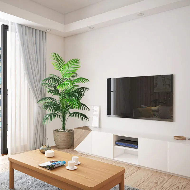Modern living room with a TV, coffee table, and decorative plant.