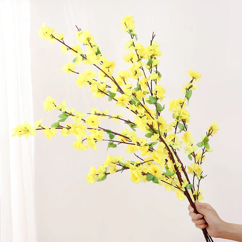 Bouquet of yellow flowers held by a hand against a white background